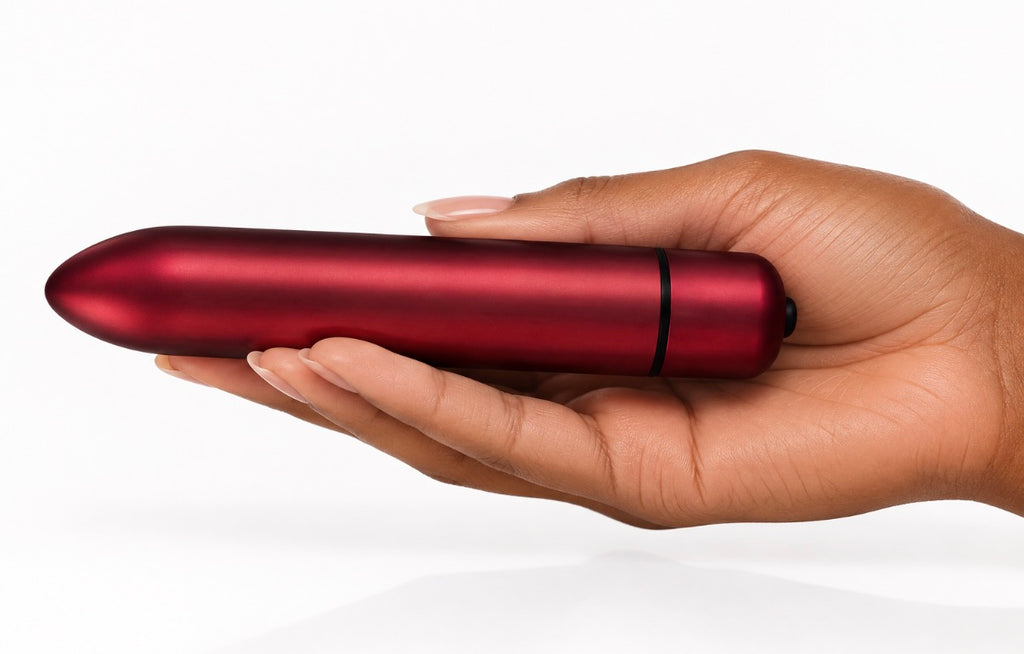 A hand holding a sleek, metallic red personal massager against a clean white background.
